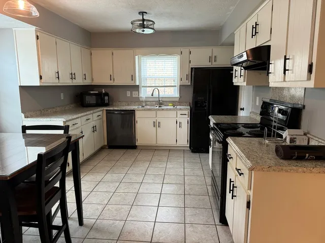 a kitchen with a stove a sink and white cabinets