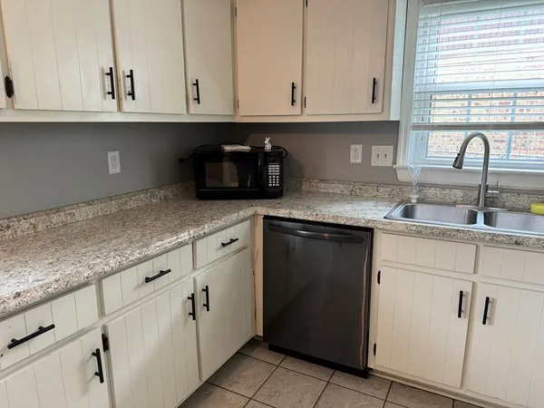 a kitchen with granite countertop white cabinets and sink