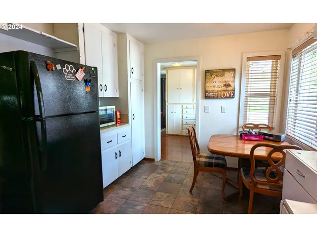 a kitchen with stainless steel appliances granite countertop a refrigerator a sink dishwasher a dining table and chairs with wooden floor