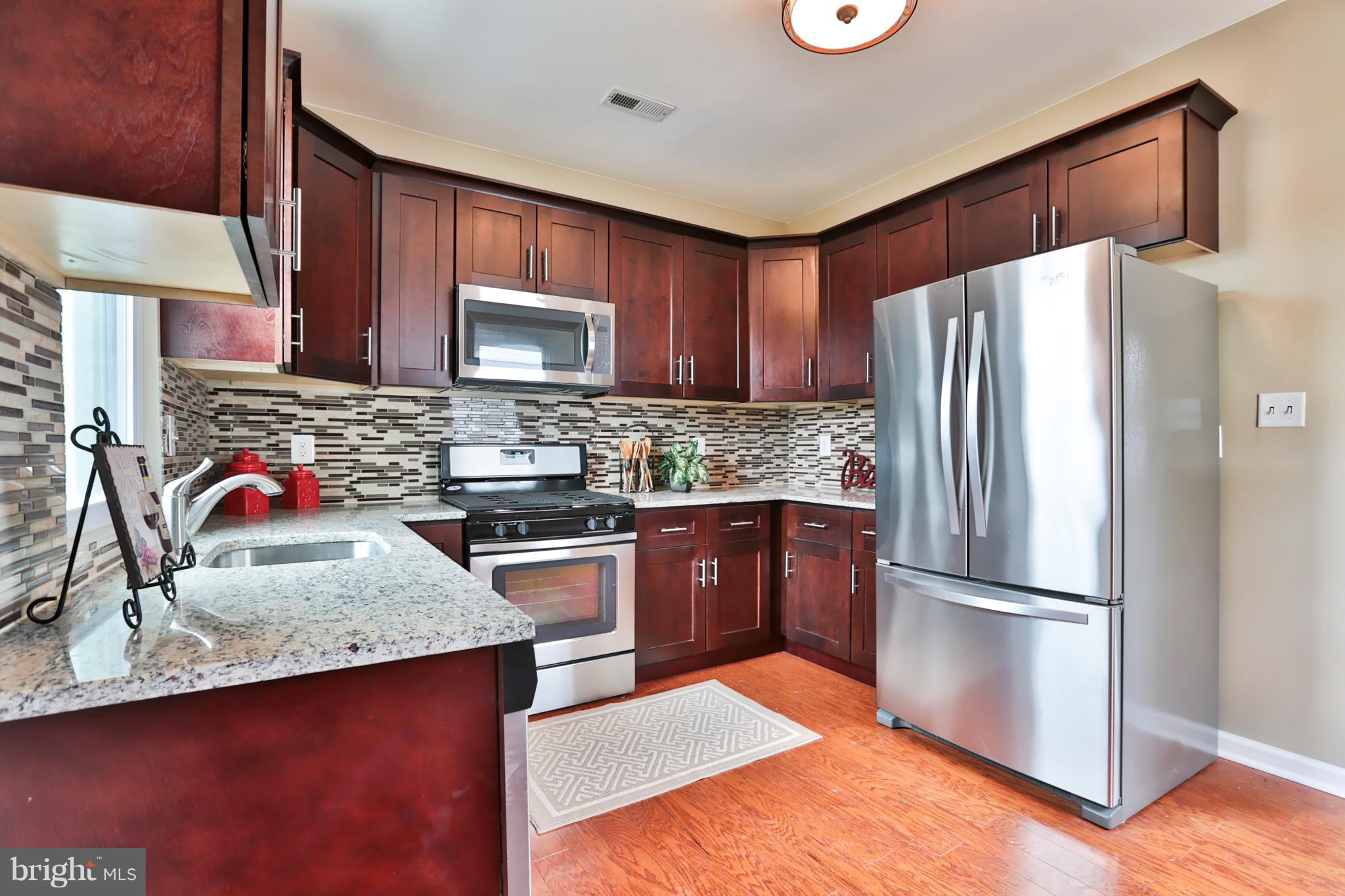 3710 Barrington Road Baltimore, MD 21215 - Photo 7 of 25 a kitchen with granite countertop stainless steel appliances and wooden cabinets