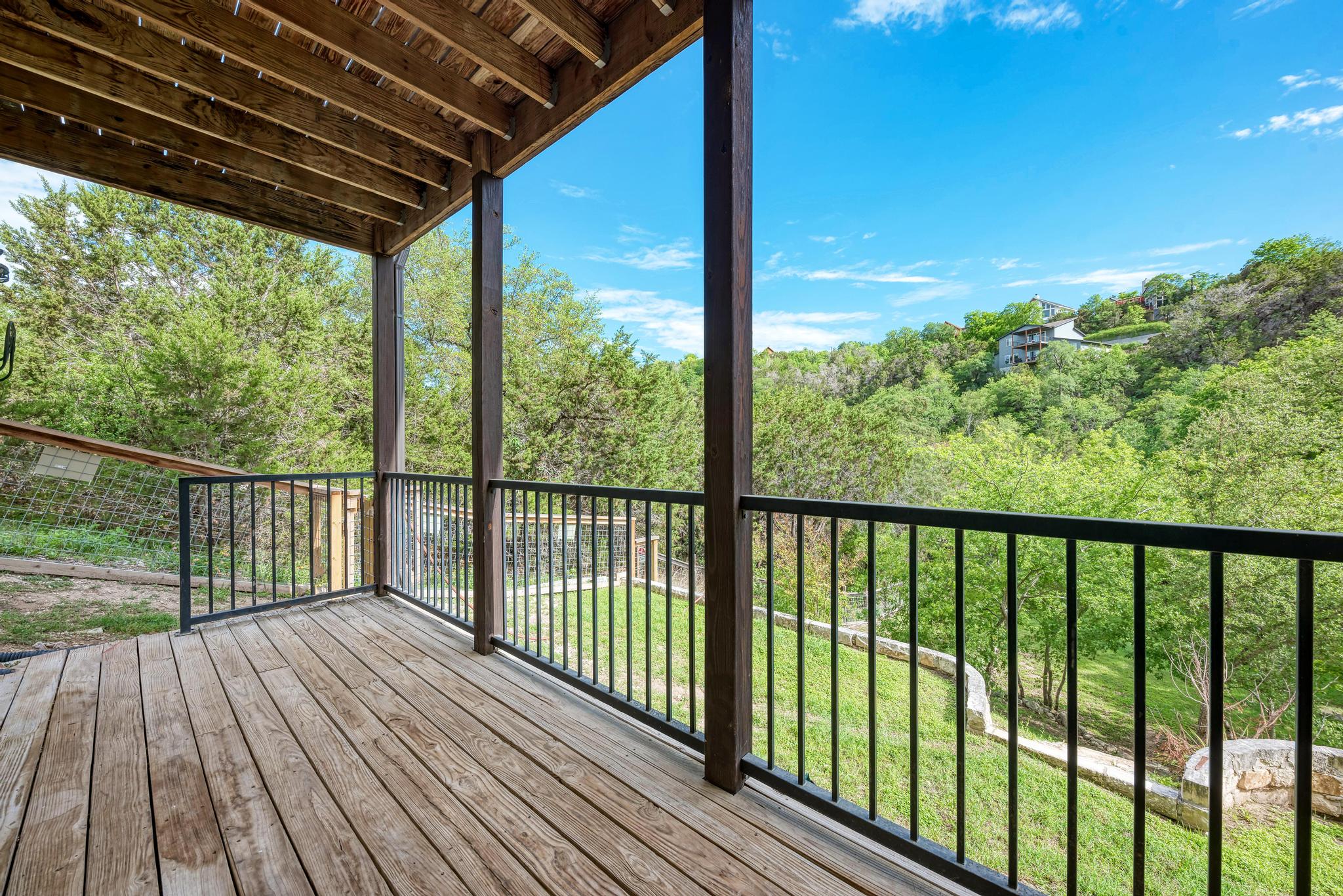 2605 Indian Creek Road Austin, TX 78734 - Photo 29 of 33 Expansive wood-finish deck with black metal railings, supported by substantial wood pillars and an exposed beam ceiling