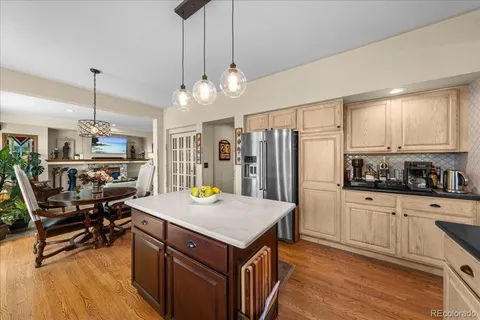 a kitchen with a refrigerator a stove a sink dishwasher a dining table and chairs with wooden floor
