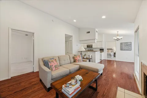 a living room with furniture and kitchen view with wooden floor