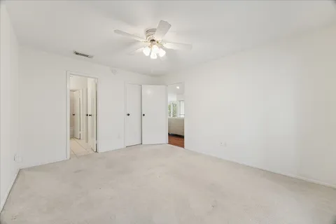 an empty room with windows and ceiling fan