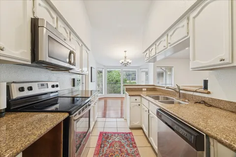 a kitchen with granite countertop a stove top oven a sink dishwasher and a dining table with wooden floor