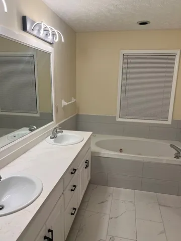 a bathroom with a tub a sink and mirror