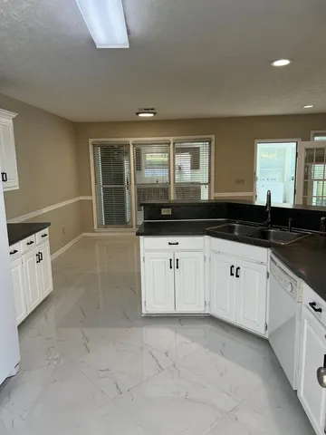 a large white kitchen with granite countertop a sink and cabinets