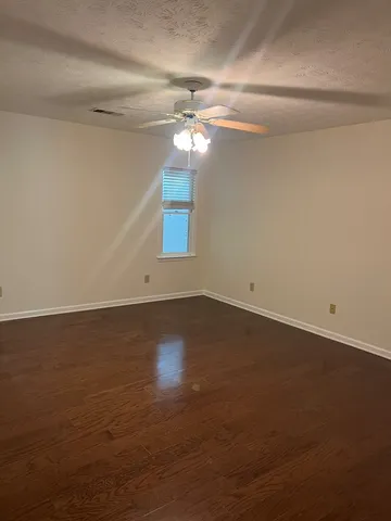 an empty room with a fan & a window
