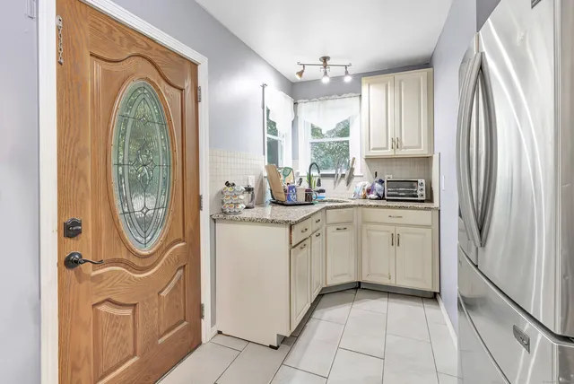 a kitchen with white cabinets and window