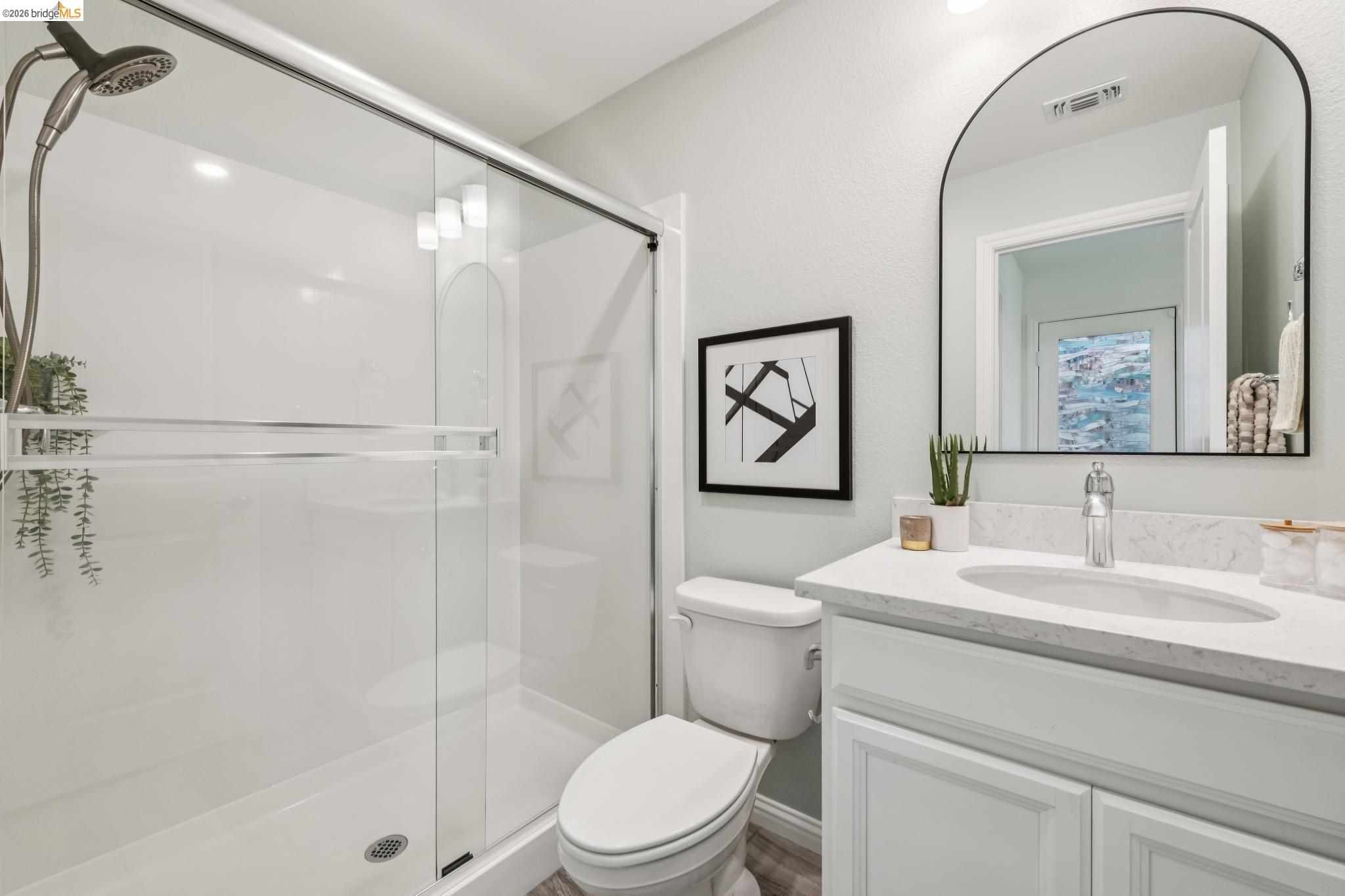 24157 Amaranth Loop Hayward, CA 94541 - Photo 12 of 63 Bathroom featuring a glass-enclosed shower with a brushed nickel shower head, a single vanity with a white countertop and undermount sink, and wood-finish flooring