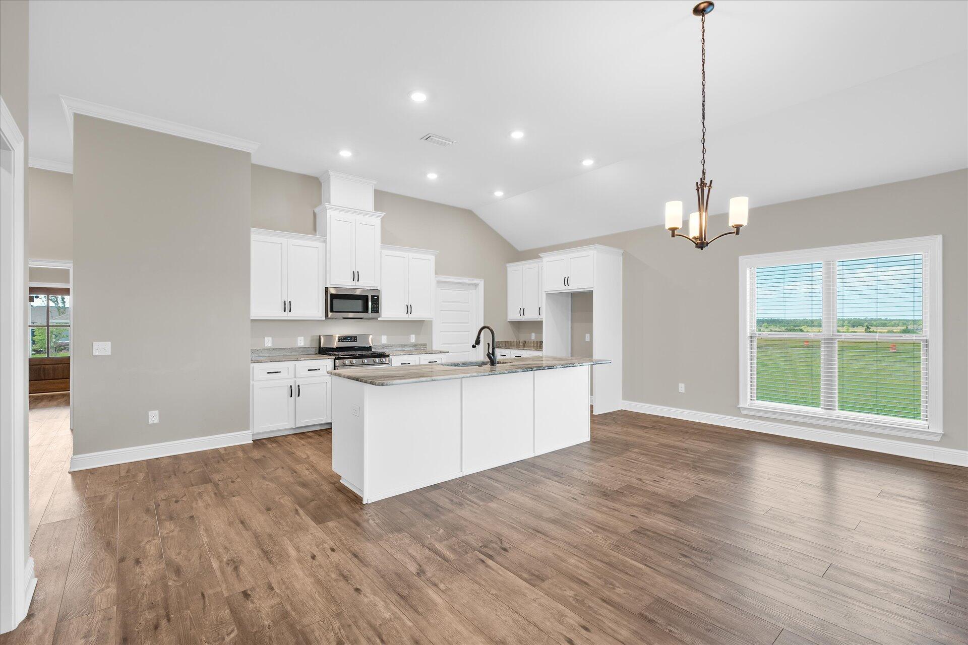 8934 Skip Stone Road Milton, FL 32583 - Photo 13 of 55 a open kitchen with granite countertop a stove a sink a center island a refrigerator and a wooden floor