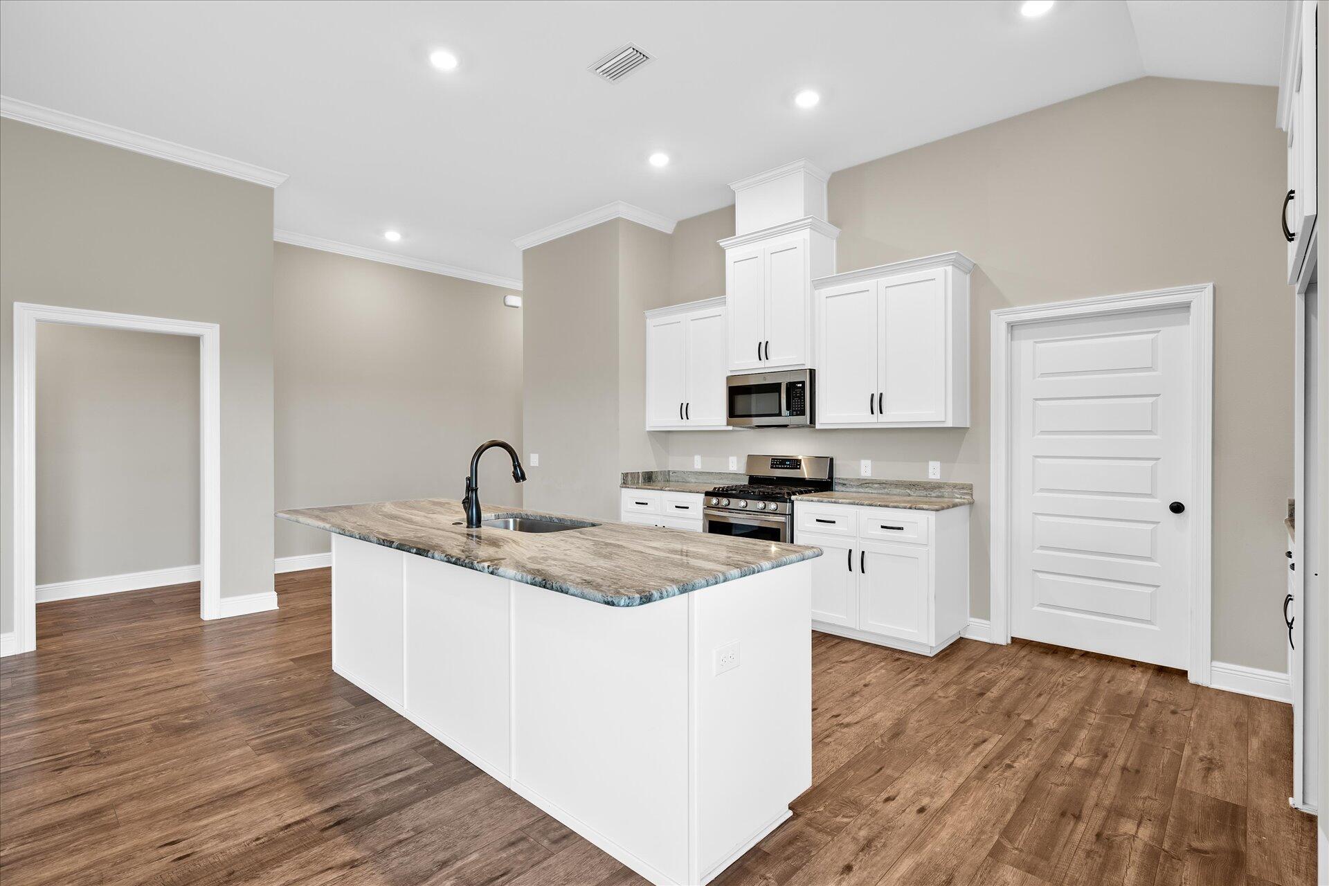 8934 Skip Stone Road Milton, FL 32583 - Photo 17 of 55 a kitchen with stainless steel appliances granite countertop a sink dishwasher a refrigerator and white cabinets with wooden floor