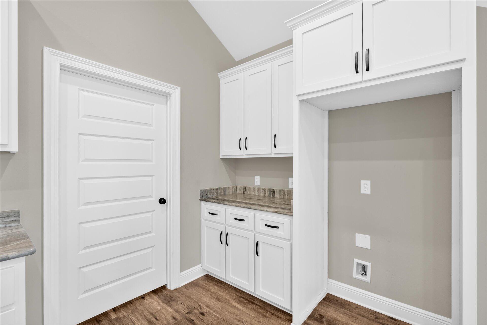 8934 Skip Stone Road Milton, FL 32583 - Photo 21 of 55 a kitchen with white cabinets and wooden floor