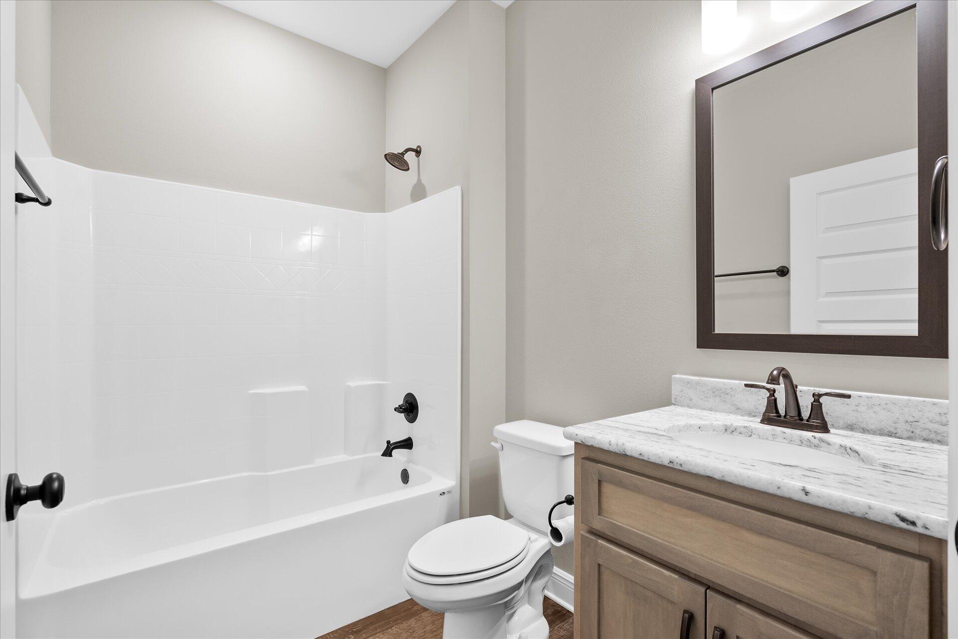 8934 Skip Stone Road Milton, FL 32583 - Photo 37 of 55 a bathroom with a granite countertop toilet a sink and a bathtub