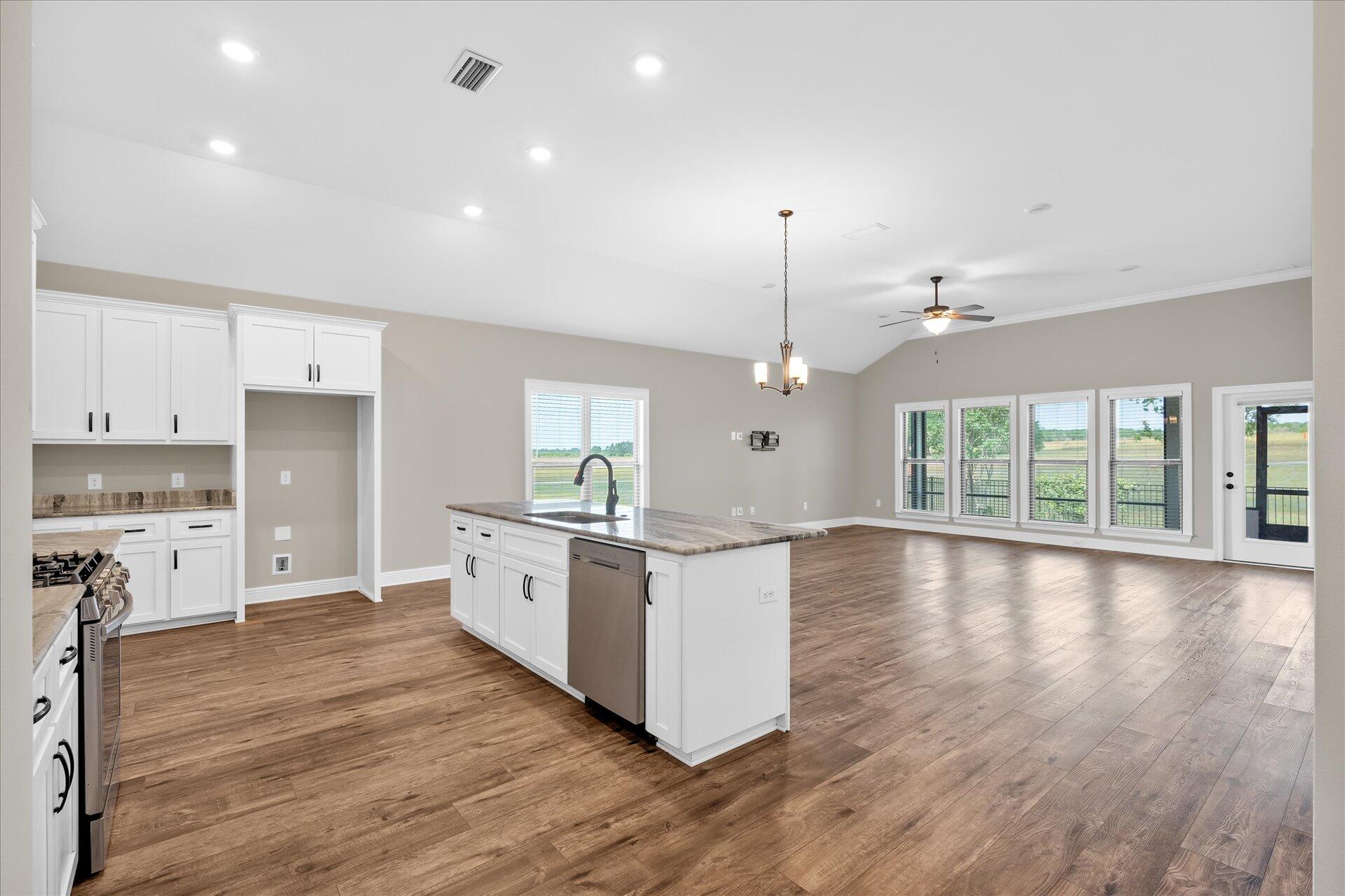 8934 Skip Stone Road Milton, FL 32583 - Photo 9 of 55 a large kitchen with granite countertop a stove top oven a sink a counter space and wooden floor