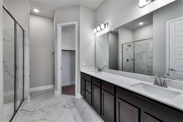 a spacious bathroom with a double vanity sink a large mirror and a shower