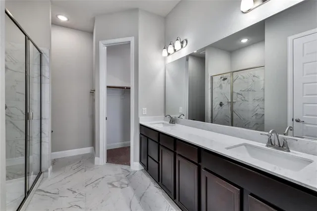 a spacious bathroom with a double vanity sink a large mirror and a shower
