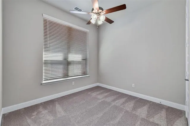an empty room with a window and a fan