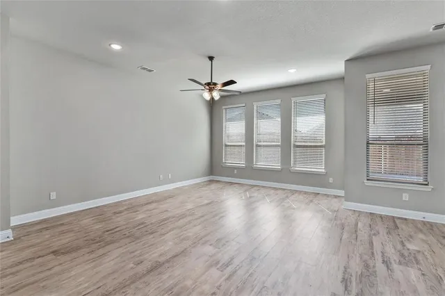 a view of an empty room with a window and wooden floor