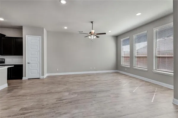 a view of an empty room with a window and a kitchen