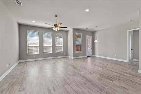 a view of an empty room with a window and wooden floor