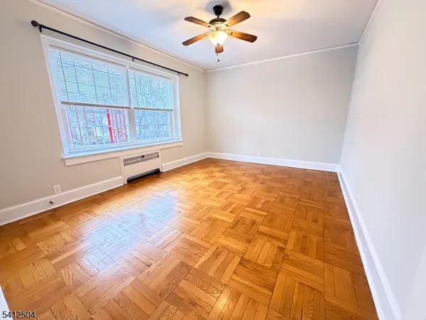 a view of an empty room with chandelier fan and wooden floor