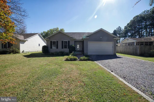 a front view of a house with a yard and large tree