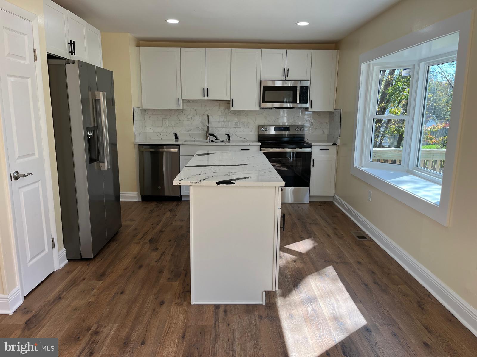 6706 Surratts Road Clinton, MD 20735 - Photo 4 of 24 a kitchen with a refrigerator a stove top oven a sink and dishwasher with wooden floor