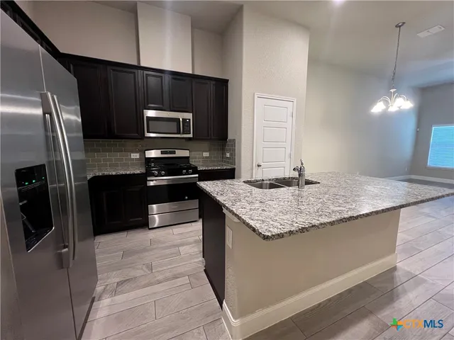 a kitchen with stainless steel appliances granite countertop a sink stove and refrigerator