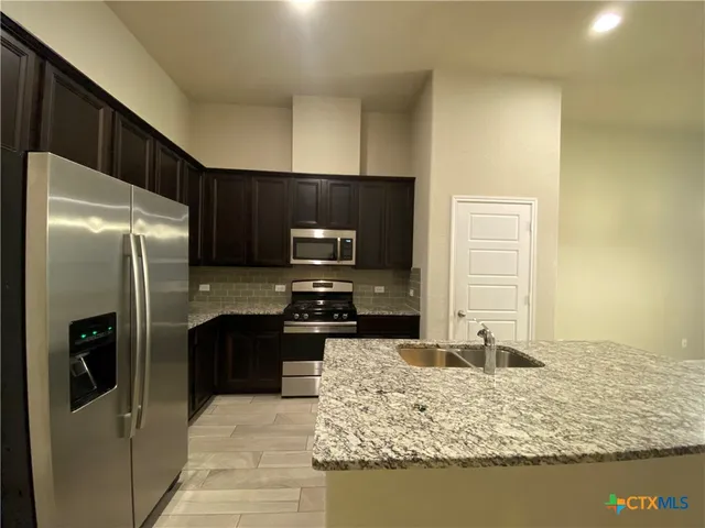 a kitchen with stainless steel appliances granite countertop a refrigerator stove and oven