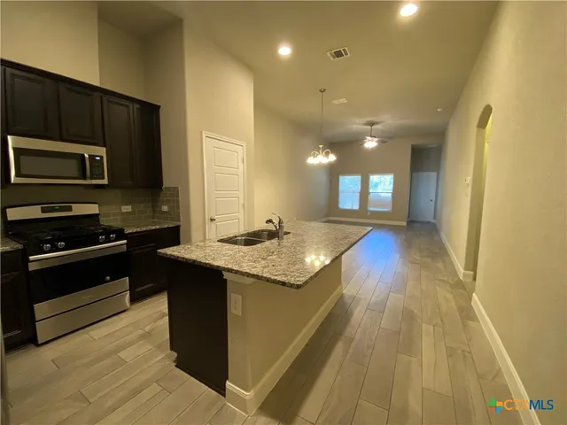 a kitchen with kitchen island granite countertop stainless steel appliances stove microwave and cabinets