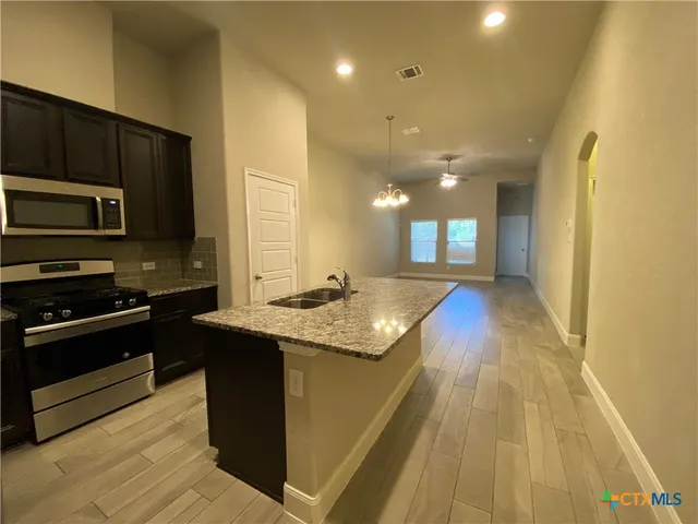 a kitchen with stainless steel appliances granite countertop a sink a stove top oven a counter space and cabinets