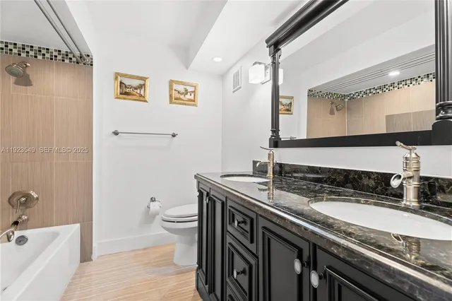 a bathroom with a granite countertop sink a toilet a mirror and shower