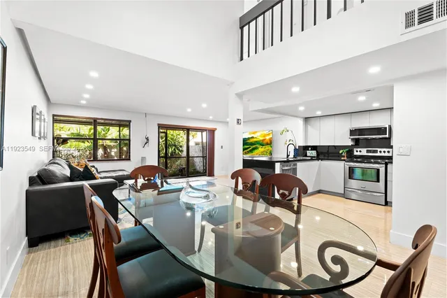 a living room with kitchen couches and kitchen view with wooden floor