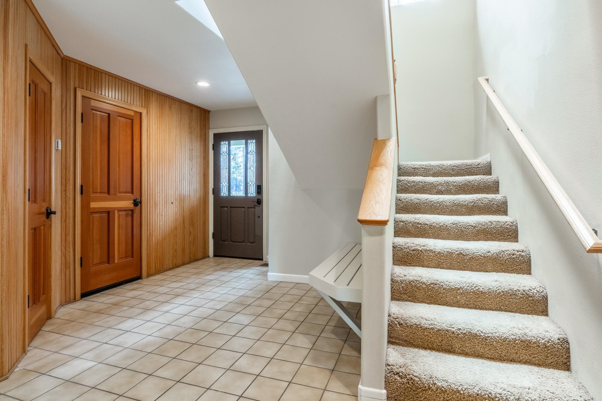 272 Ridge Way Mammoth Lakes, CA 93546 - Photo 9 of 55 Entryway featuring tiled flooring, beadboard wall paneling, recessed lighting, a stained-glass entry door, and a carpeted staircase with wood handrails