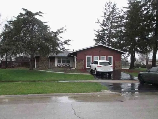 a front view of a house with a garden and trees