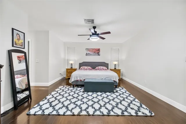 a bedroom with a bed and dresser with wooden floor
