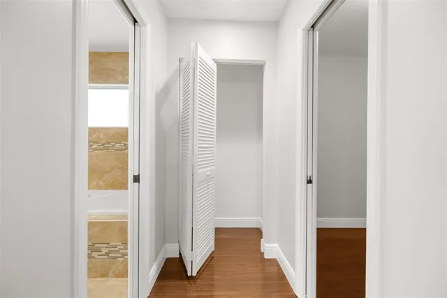 a view of a hallway with wooden floor and a bathroom