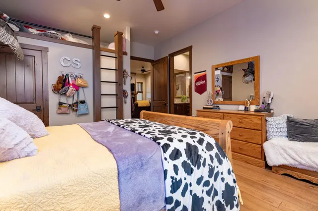 a bedroom with a bed and dresser with wooden floor