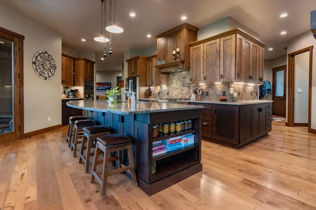 a room with stainless steel appliances kitchen island granite countertop furniture wooden floor and a view of kitchen