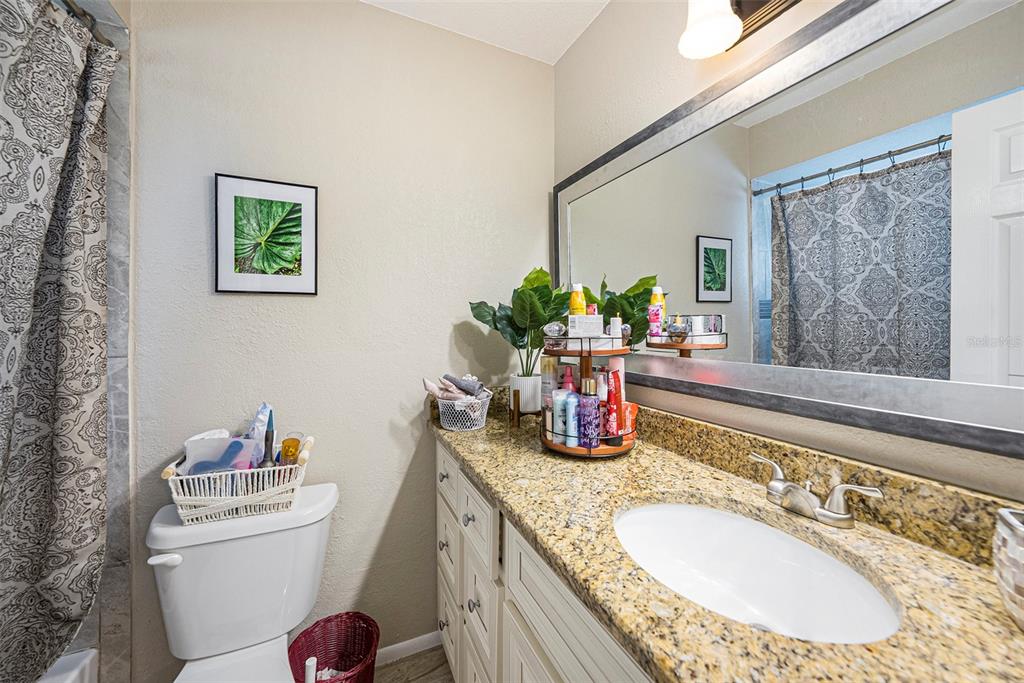 4805 Grove Point Drive Tampa, FL 33624 - Photo 17 of 35 a bathroom with a granite countertop sink a toilet and a mirror