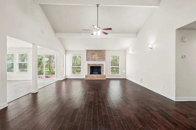 an empty room with wooden floor fireplace and windows