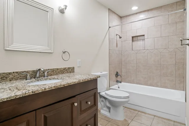 a bathroom with a granite countertop sink a toilet and bathtub