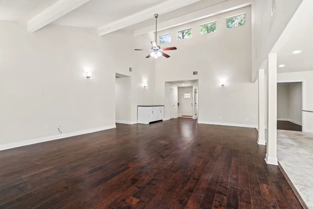 a view of an empty room with wooden floor and a ceiling fan