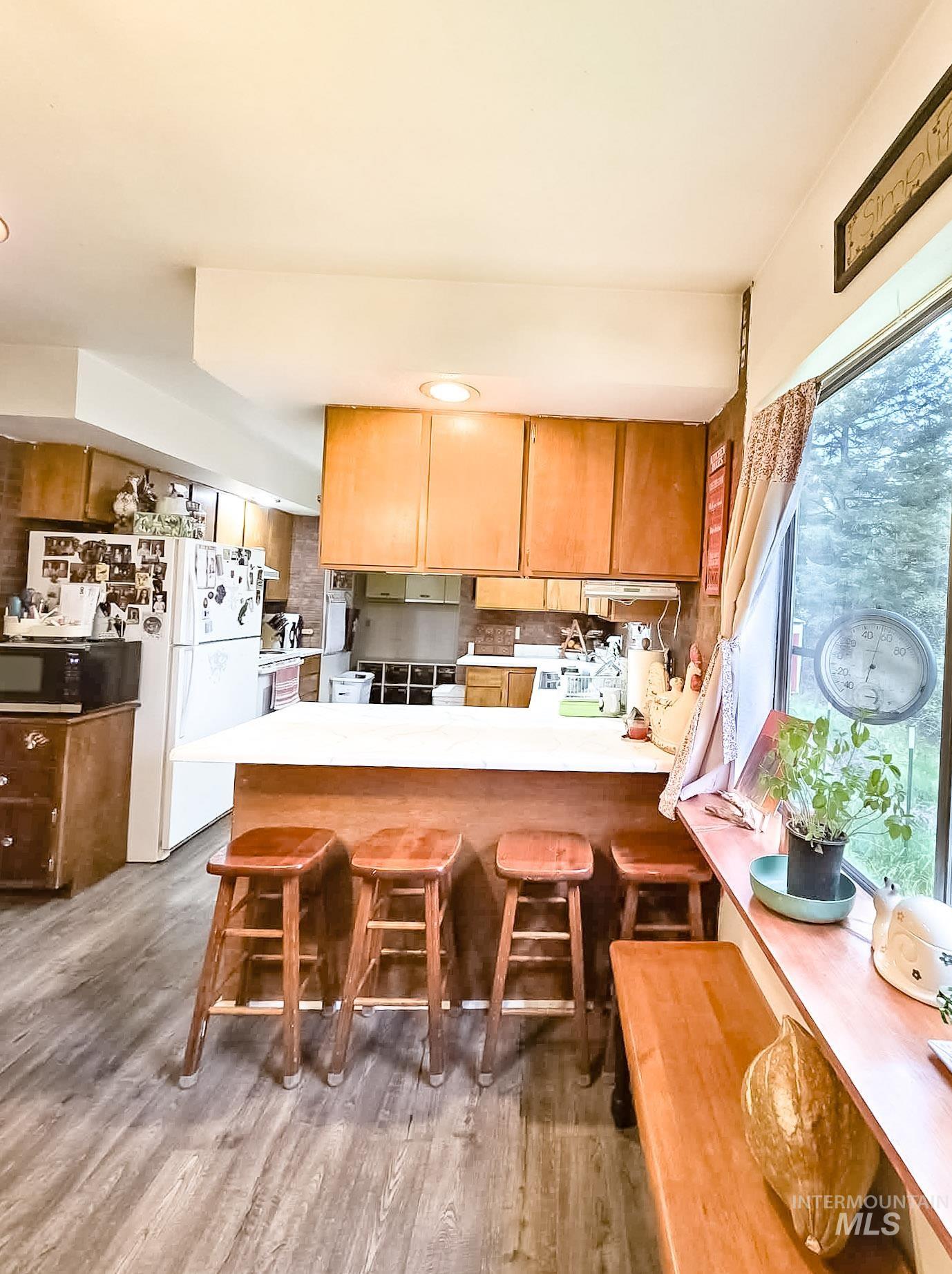1650 Wells Bench Road Orofino, ID 83544 - Photo 12 of 44 Kitchen featuring wood-finish flooring, a central island with countertop seating, wood cabinetry, and a window with a built-in wood bench