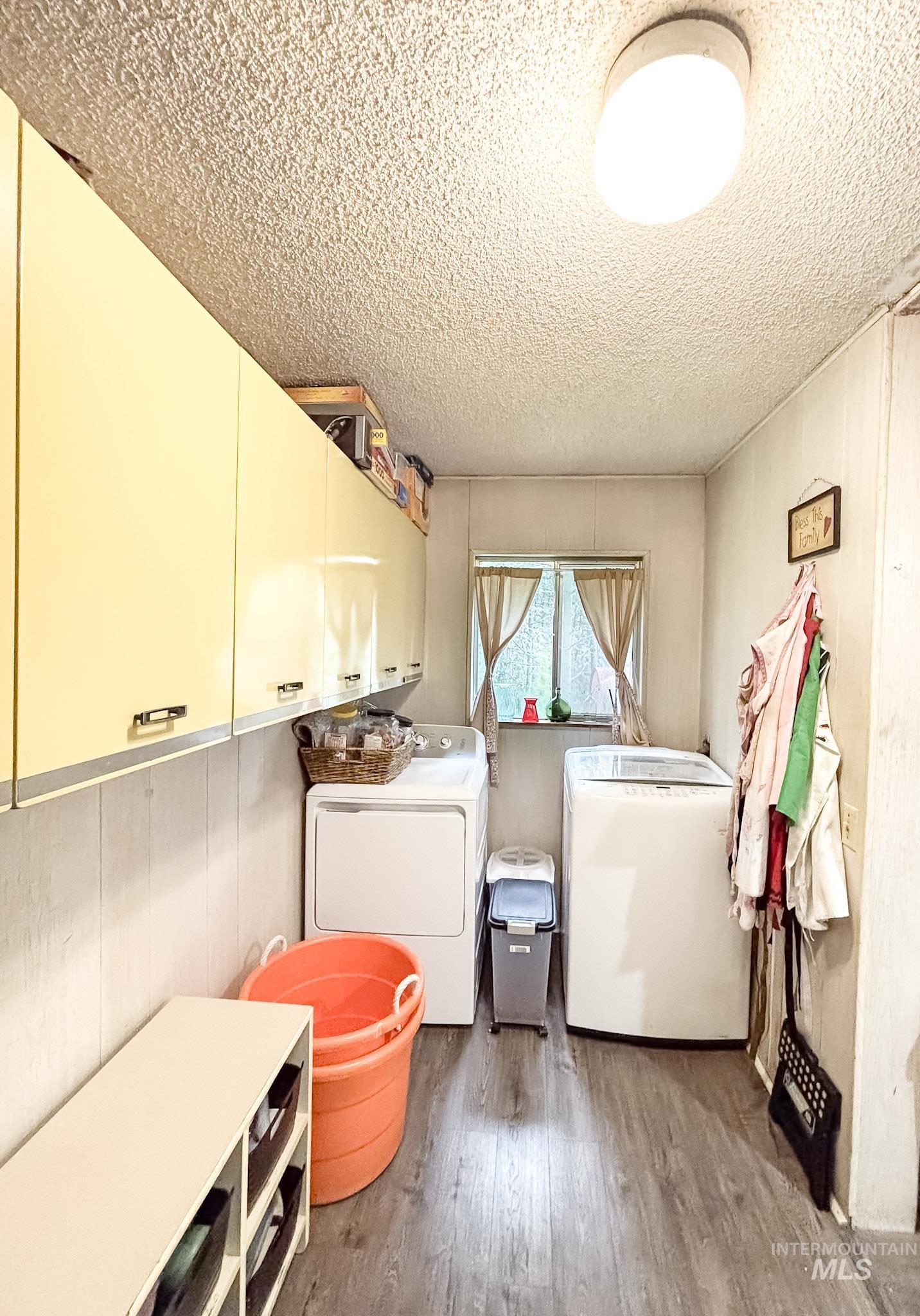 1650 Wells Bench Road Orofino, ID 83544 - Photo 14 of 44 Utility area featuring extensive overhead cabinetry, a window with natural light, and wood-finish flooring