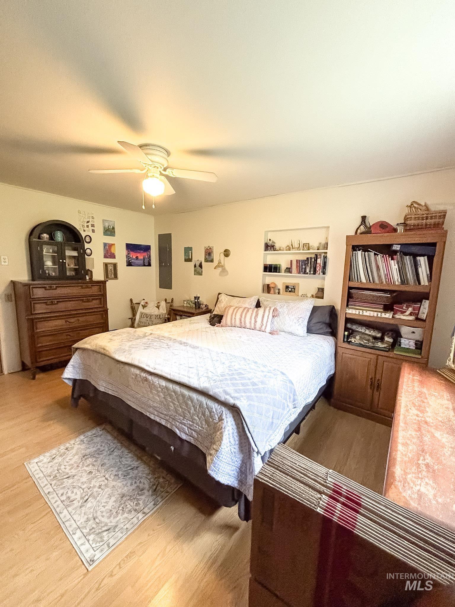 1650 Wells Bench Road Orofino, ID 83544 - Photo 22 of 44 Interior room with light wood-finish flooring, featuring a ceiling fan with integrated lighting, a built-in recessed shelving unit, and a neutral wall color