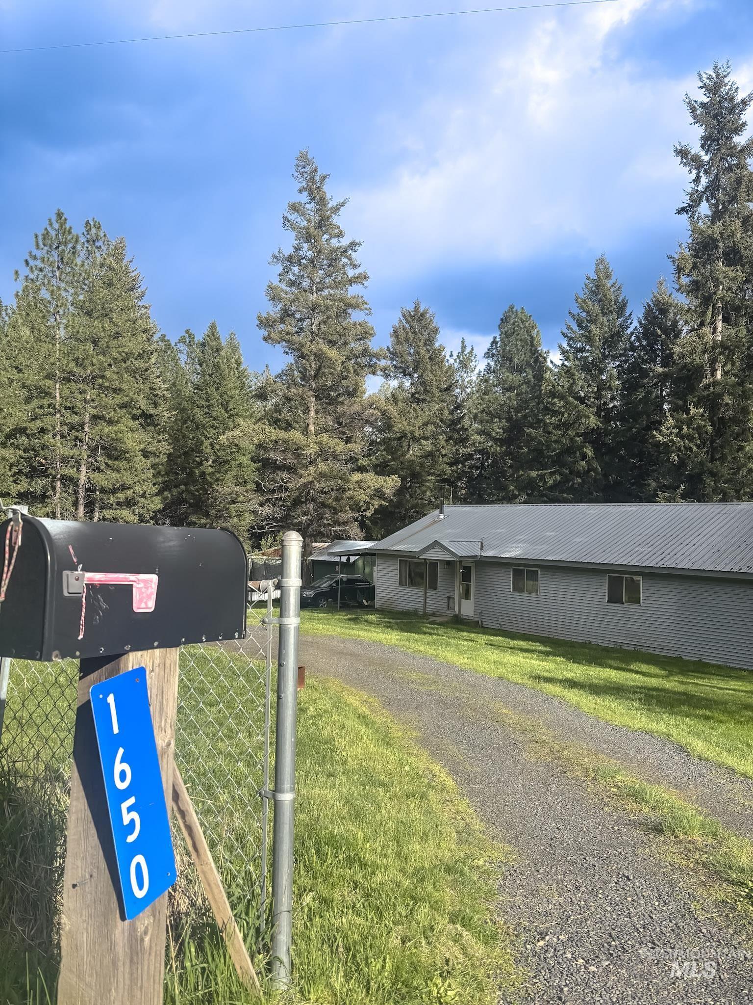 1650 Wells Bench Road Orofino, ID 83544 - Photo 37 of 44 Ranch-style residence featuring a gravel driveway, mature evergreen trees, and a chain-link fence