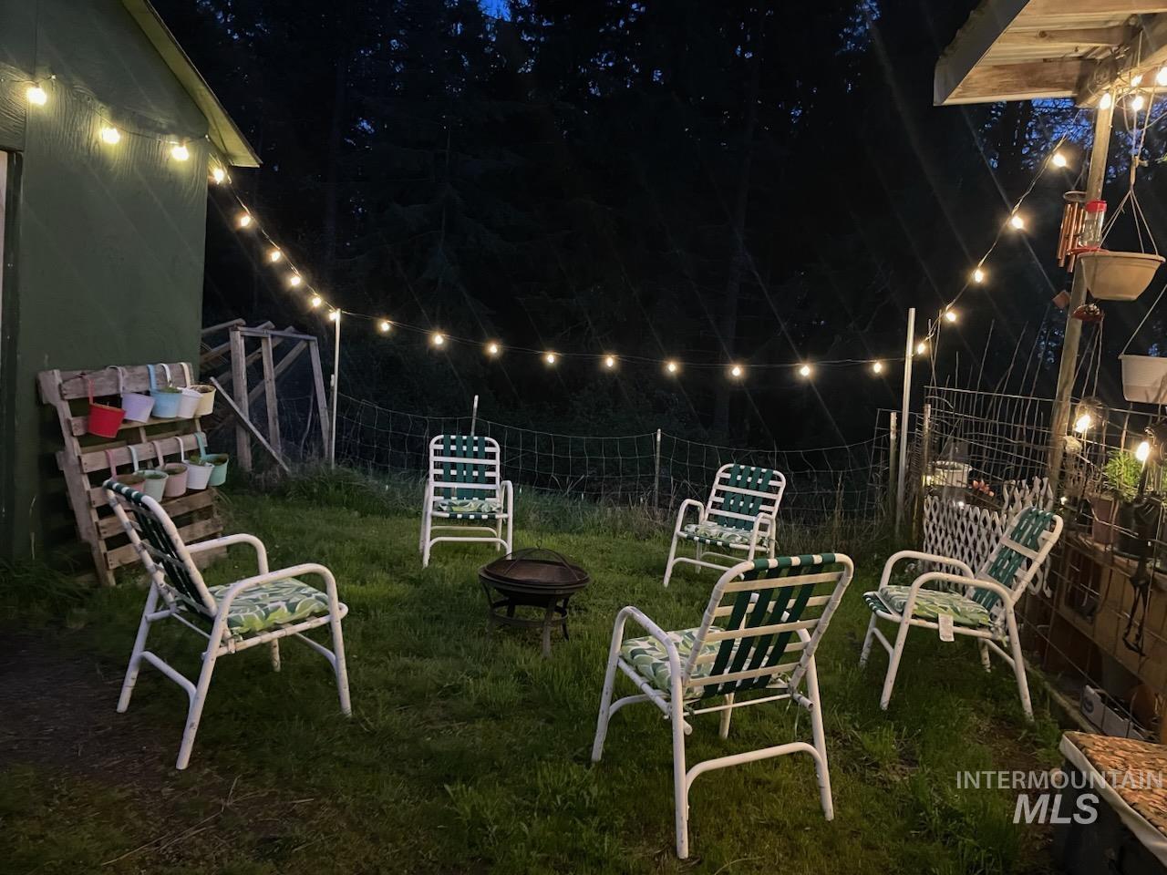 1650 Wells Bench Road Orofino, ID 83544 - Photo 44 of 44 Grassed outdoor area featuring a central fire pit, string lighting, and a green shed with a pallet-style vertical garden