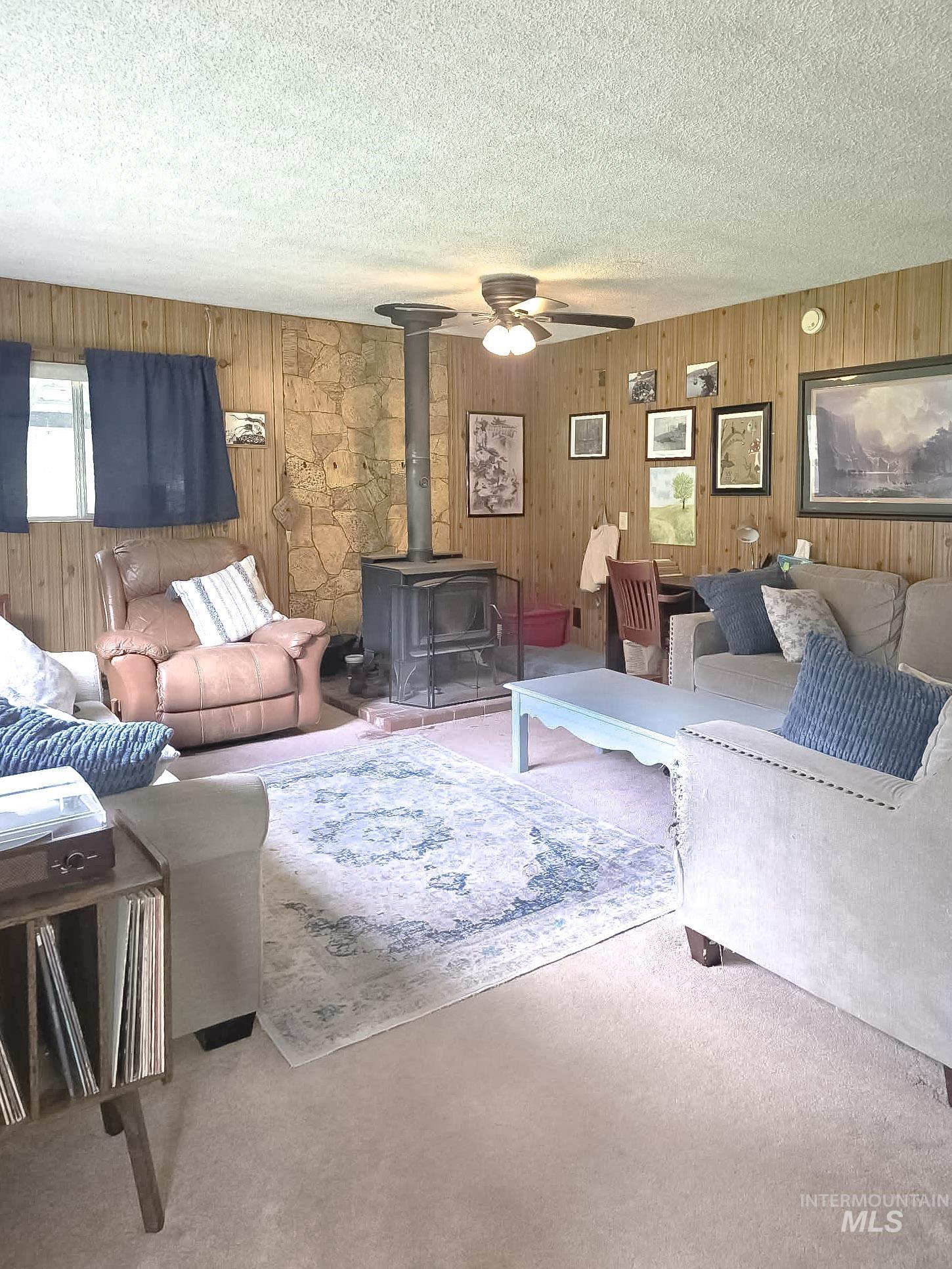 1650 Wells Bench Road Orofino, ID 83544 - Photo 6 of 44 Living area featuring wood paneling, a stone accent wall, and a freestanding wood-burning stove